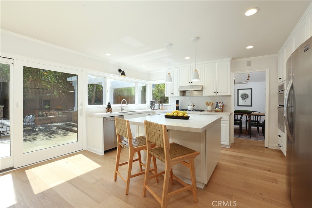 a kitchen with stainless steel appliances kitchen island granite countertop a refrigerator and a stove top oven