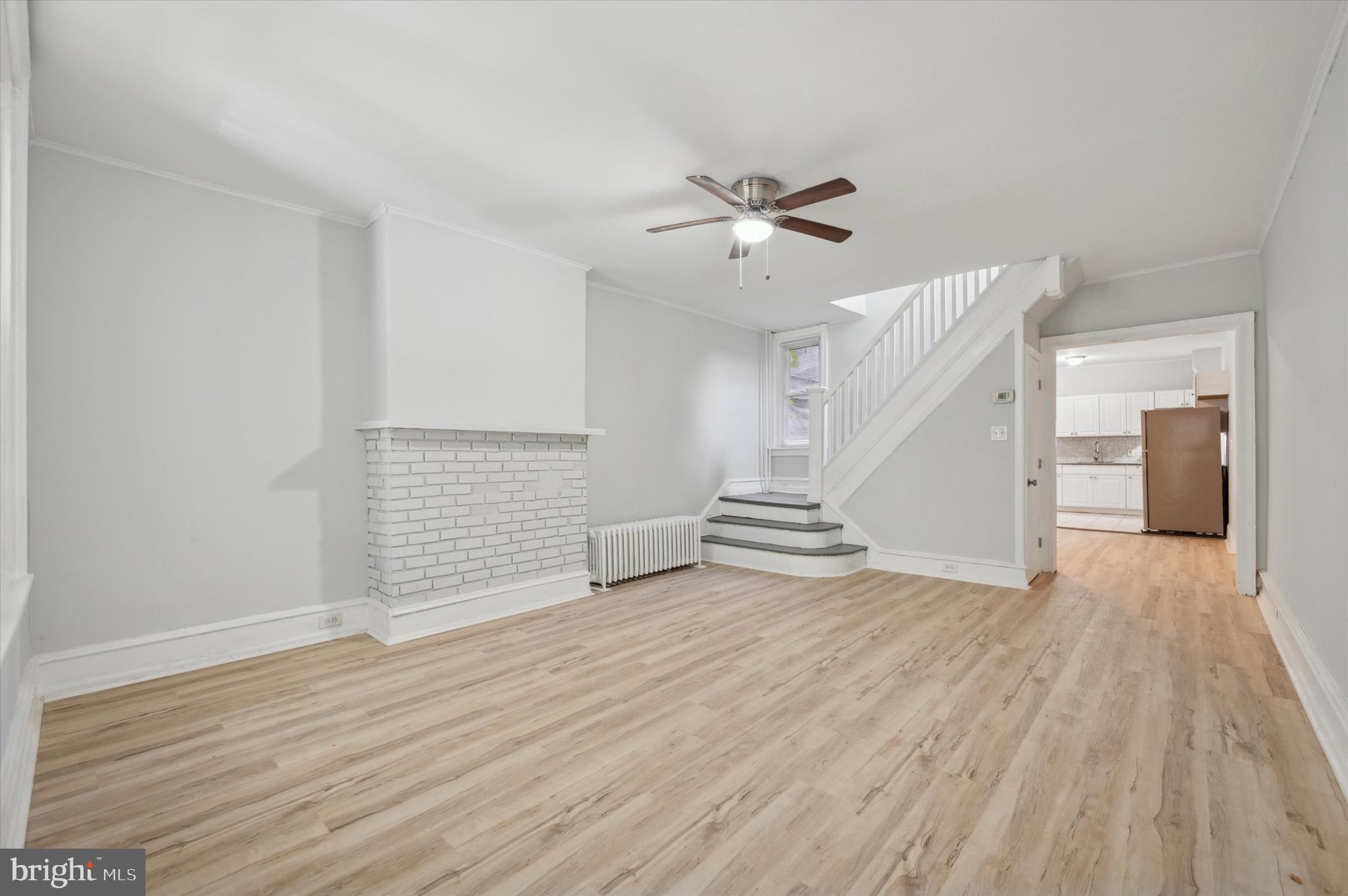 a view of an empty room with wooden floor and a ceiling fan