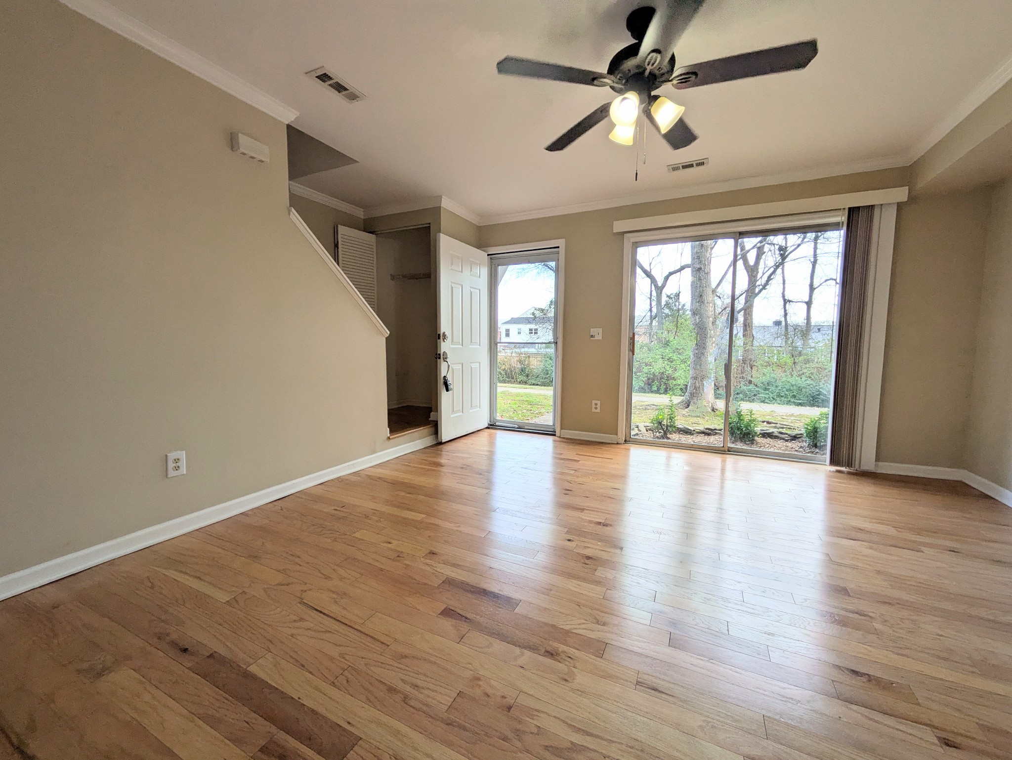 a view of an empty room with a window and wooden floor