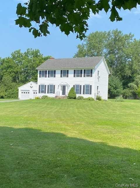 a white house with a big yard and large trees