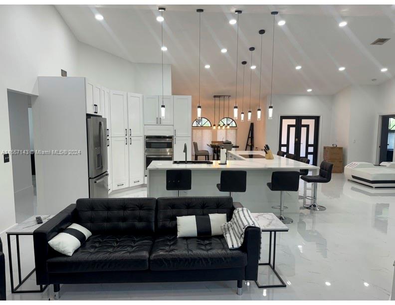 a living room with stainless steel appliances kitchen island granite countertop furniture and a rug