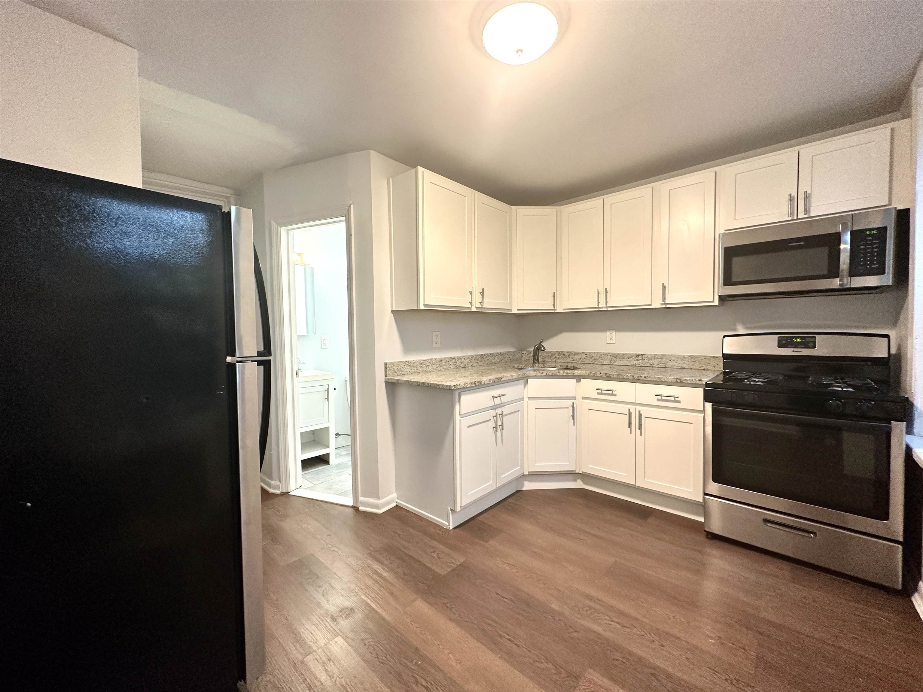 a kitchen with granite countertop white cabinets and stainless steel appliances