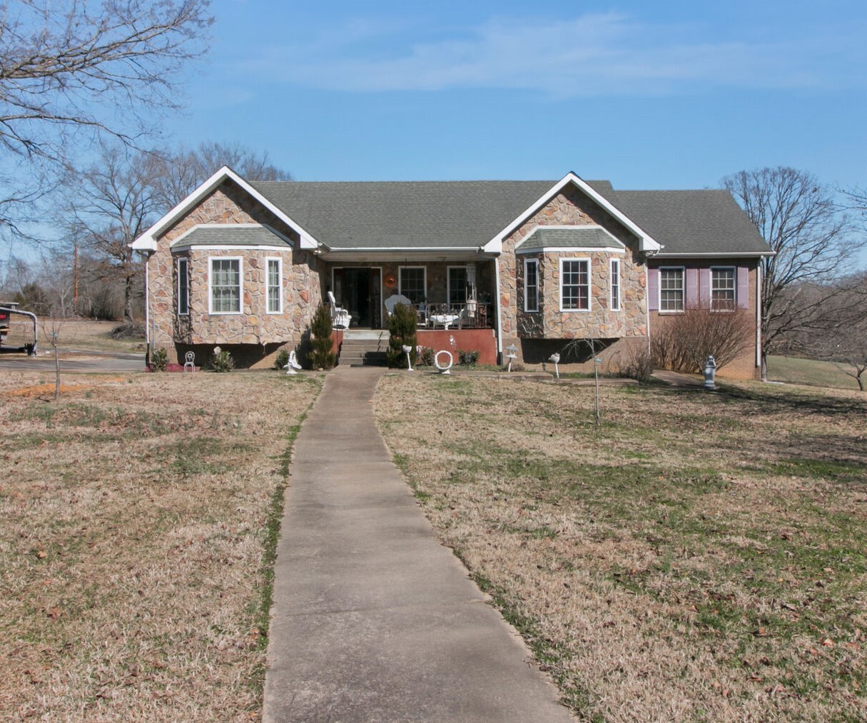 a front view of a house with a yard and large trees