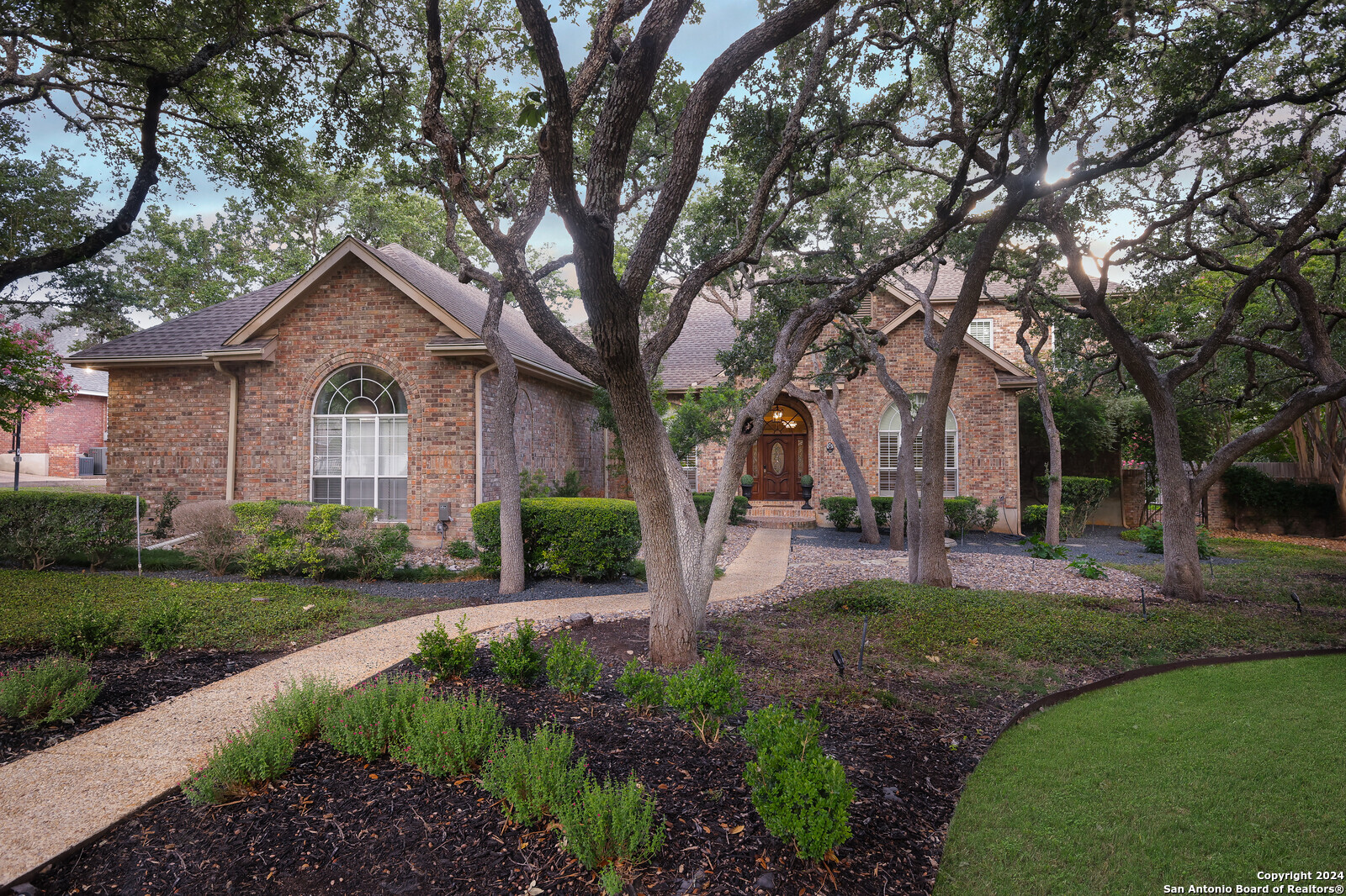 a front view of a house with garden and trees