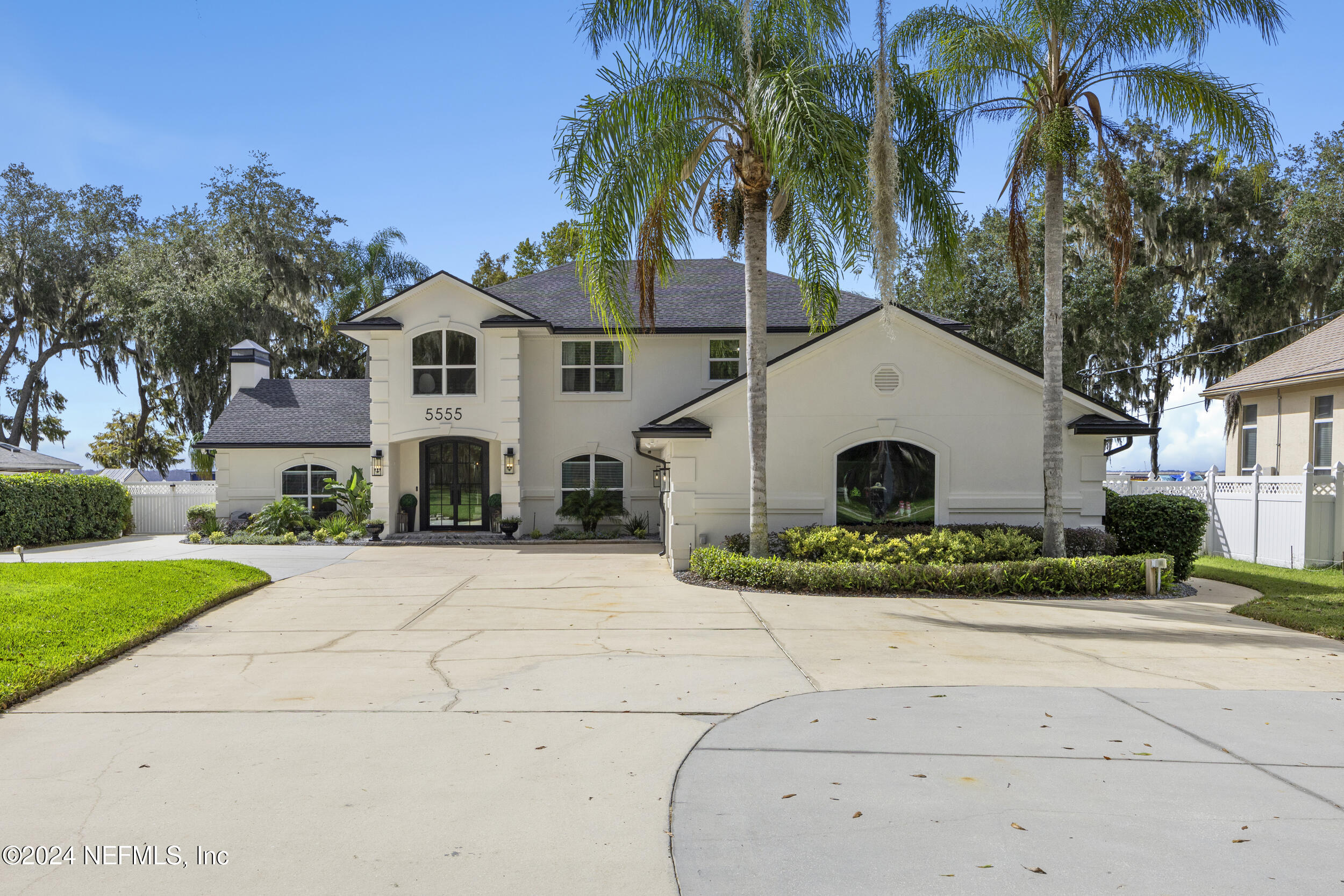 a view of a white house with a small yard and palm trees