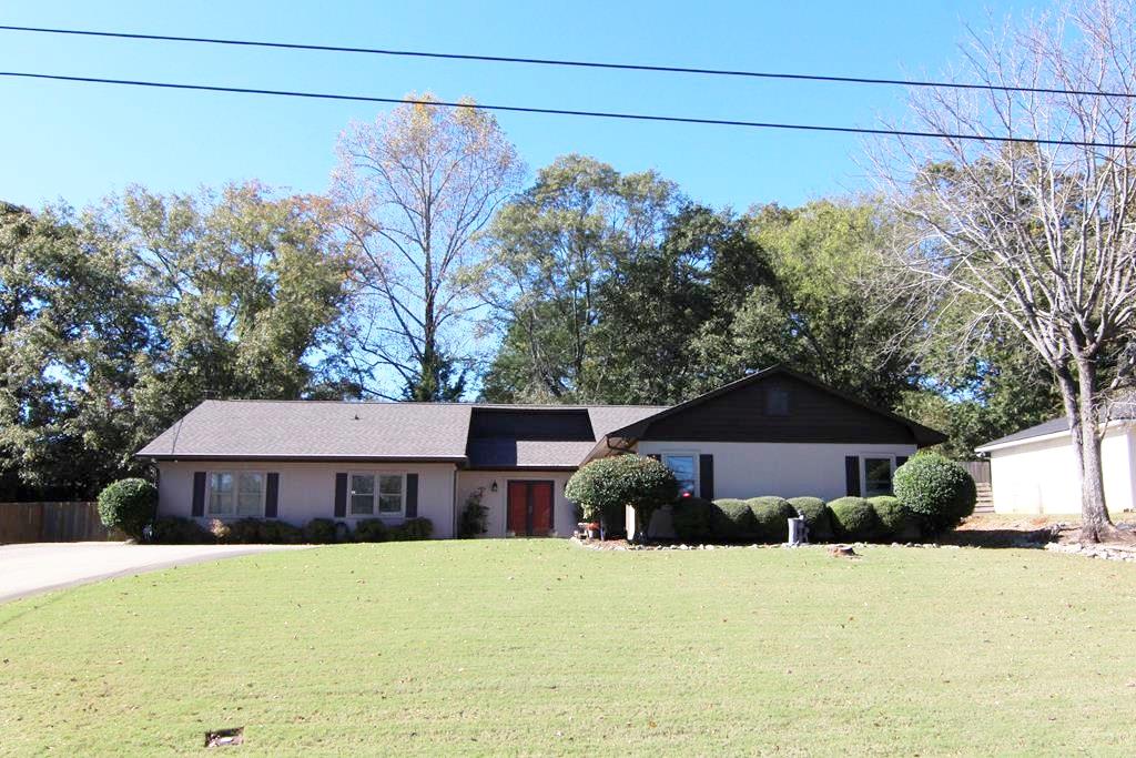 a front view of a house with a yard and a tree