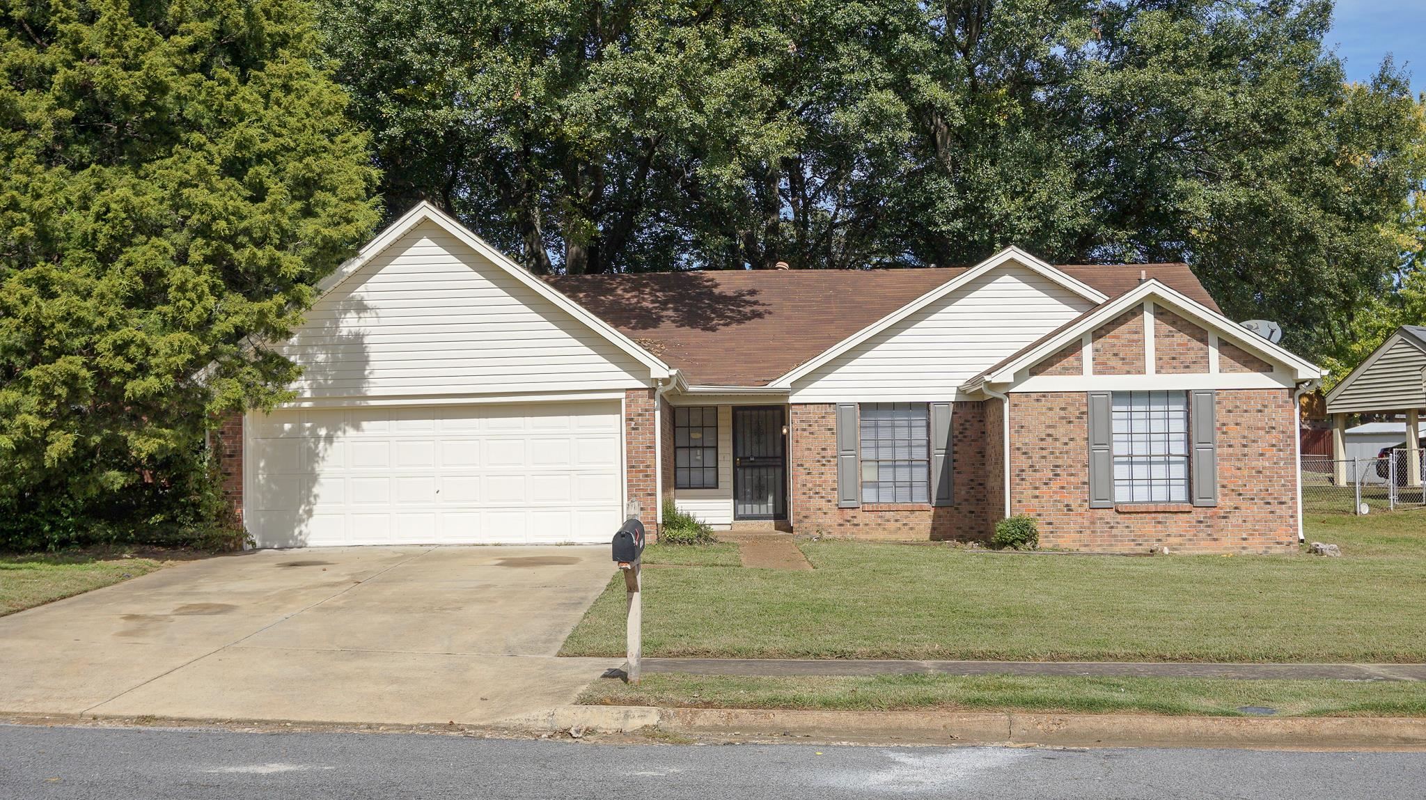 Single story home with a garage and a front lawn