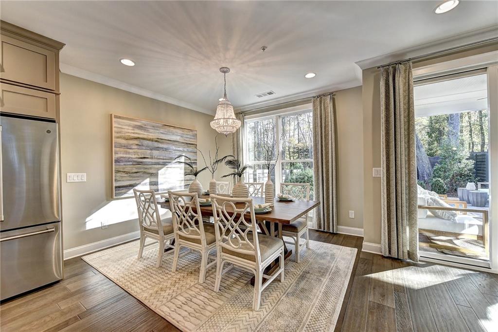 a dining room with wooden floor a chandelier a glass table and chairs