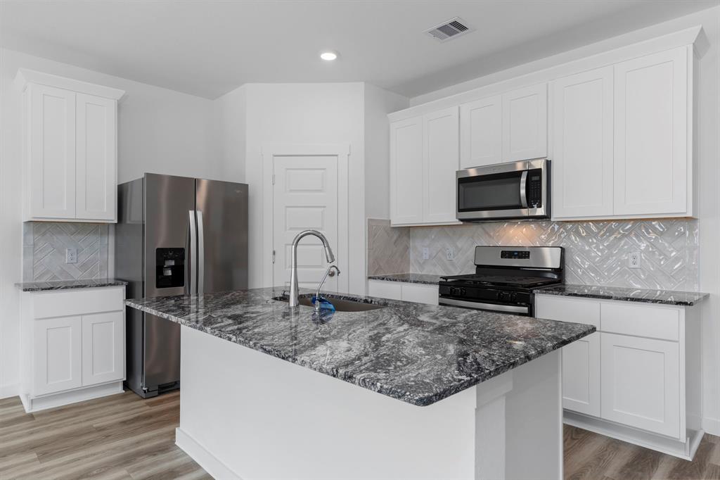 a kitchen with stainless steel appliances granite countertop a sink stove microwave and refrigerator