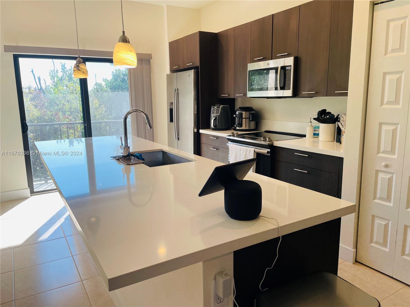 a kitchen with a sink a kitchen island a stove and a refrigerator