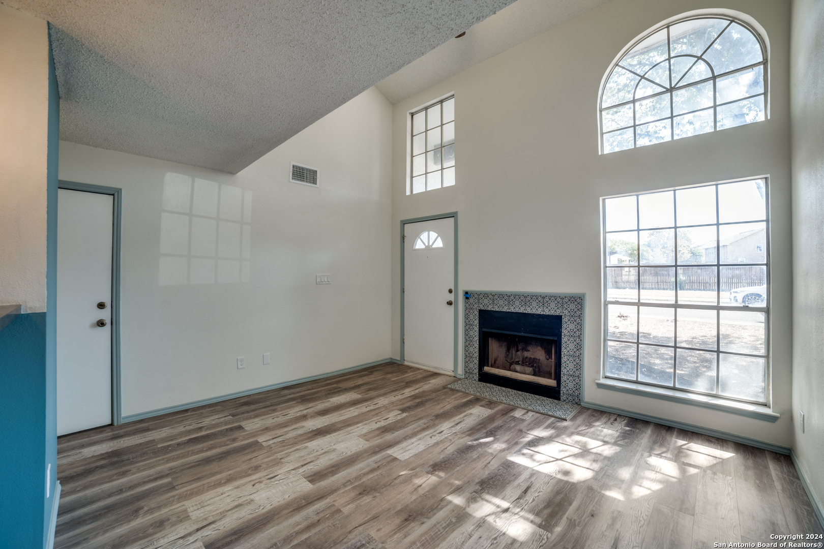 an empty room with windows and fireplace