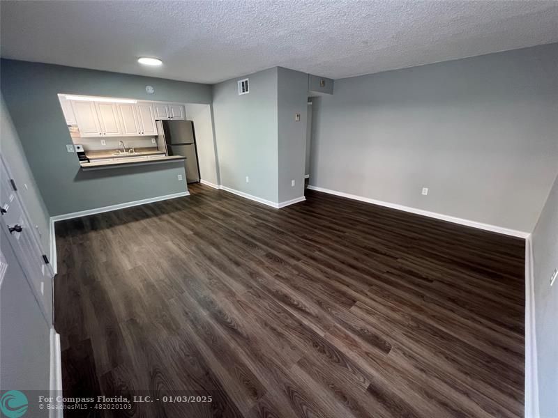 a view of empty room with wooden floor and window