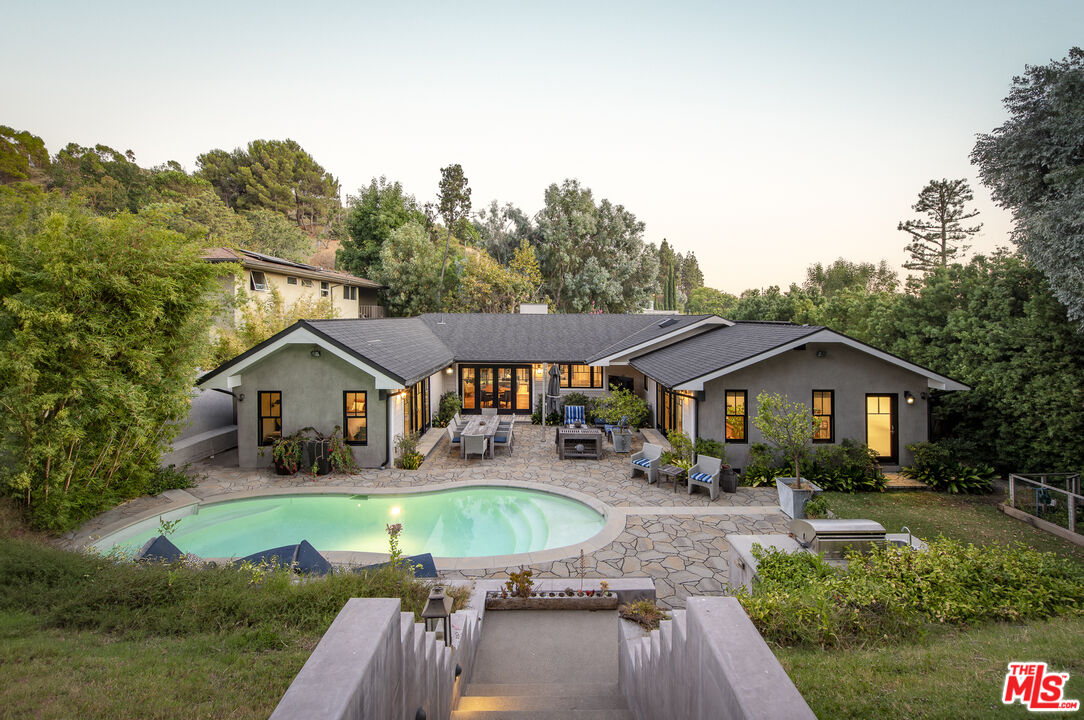 a view of a house with a big yard plants and large trees