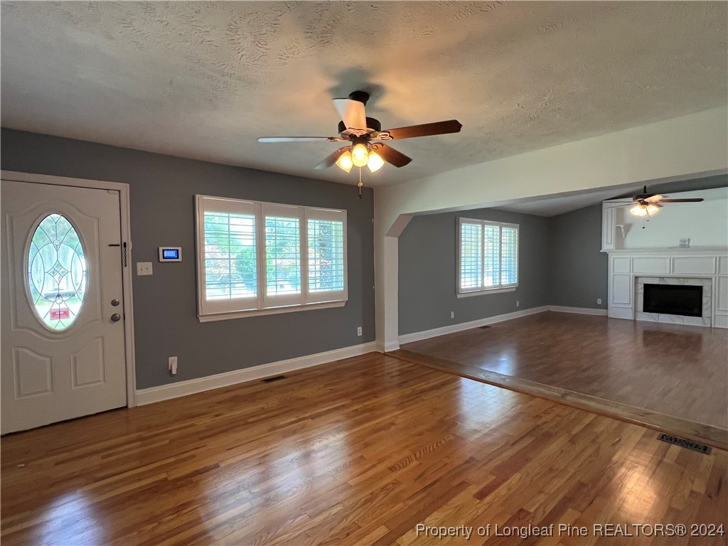 a view of an empty room with window and wooden floor