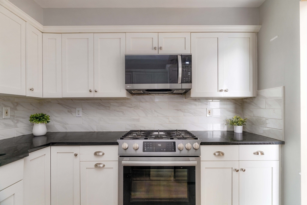 a kitchen with white cabinets and a stove top oven