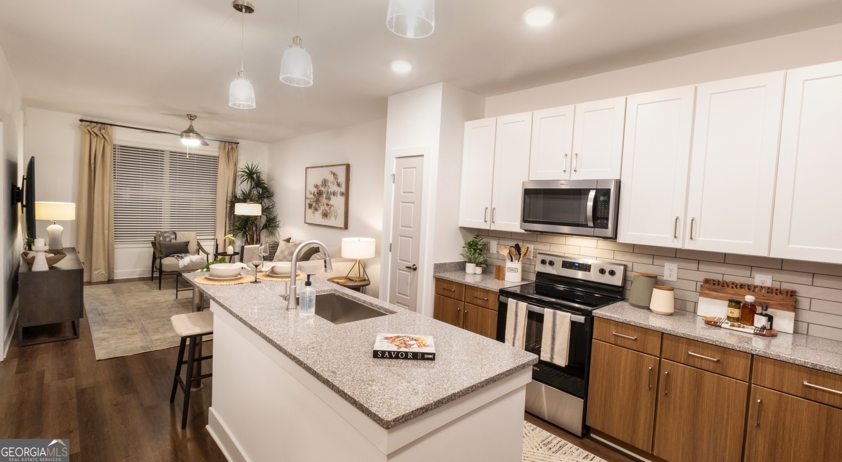 a view of a kitchen with kitchen island stainless steel appliances a sink a stove a counter top space and living room view