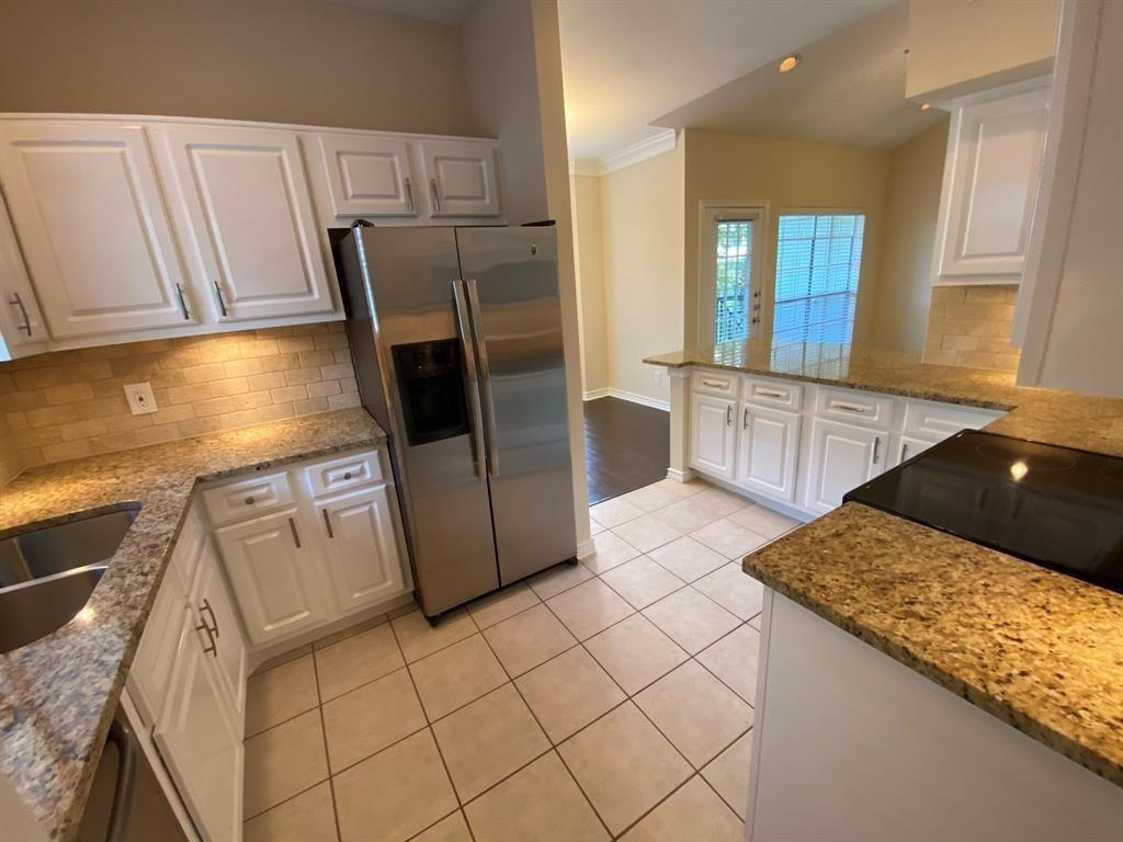 a kitchen with granite countertop white cabinets and refrigerator