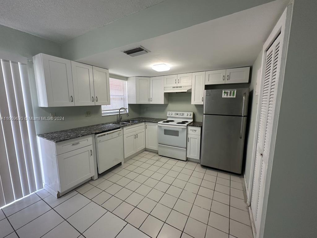 a kitchen with a refrigerator sink and cabinets