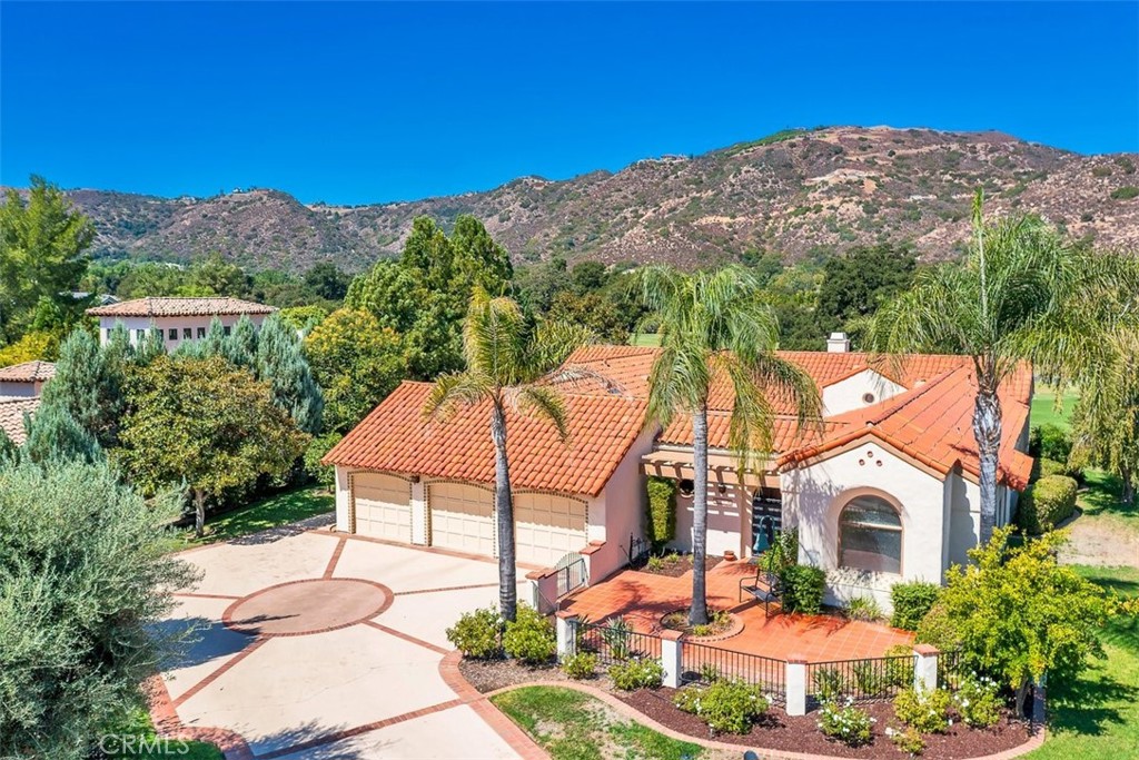 a front view of a house with a yard and mountain view in back