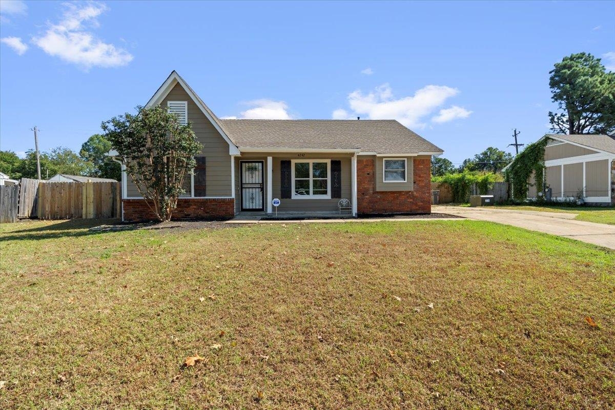 a front view of house with yard and trees in the background