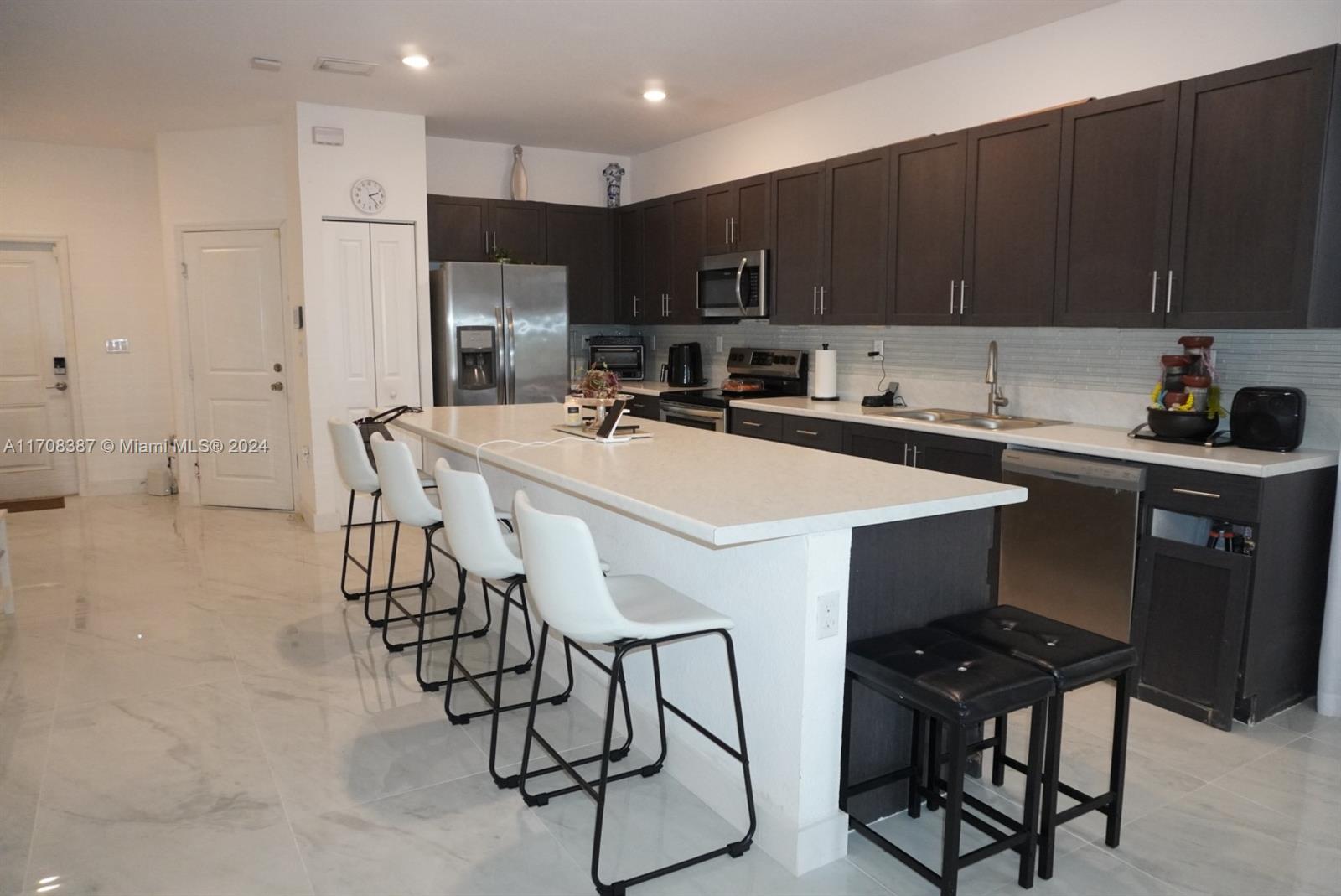 a kitchen with stainless steel appliances a table chairs refrigerator and microwave