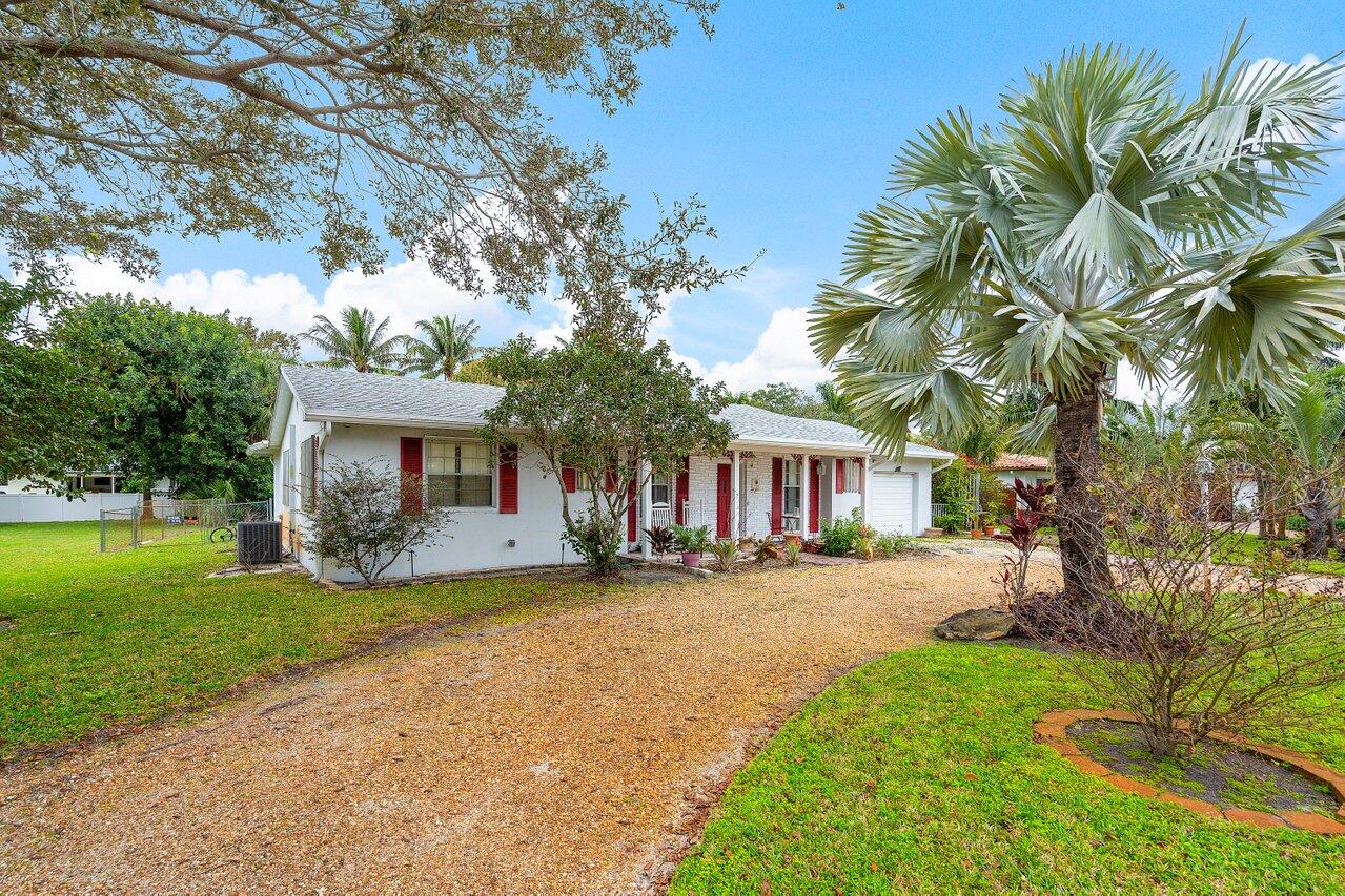 a front view of a house with a garden and trees