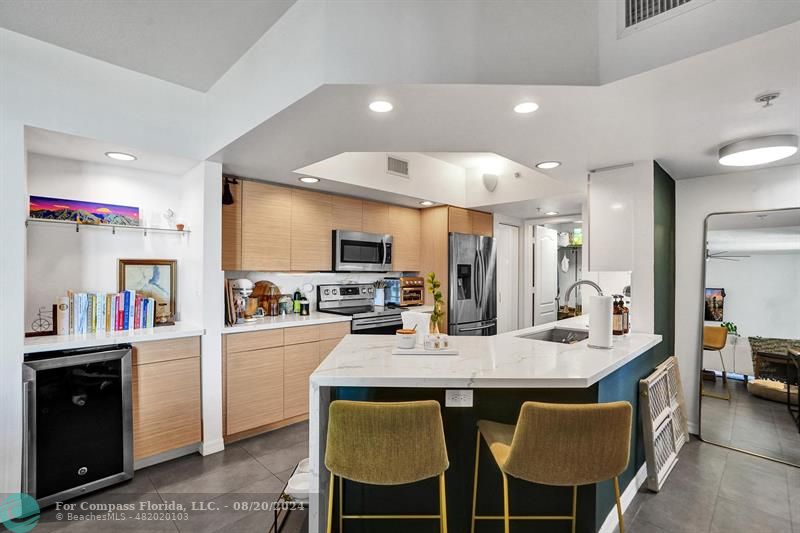 a kitchen with granite countertop a table chairs microwave and refrigerator