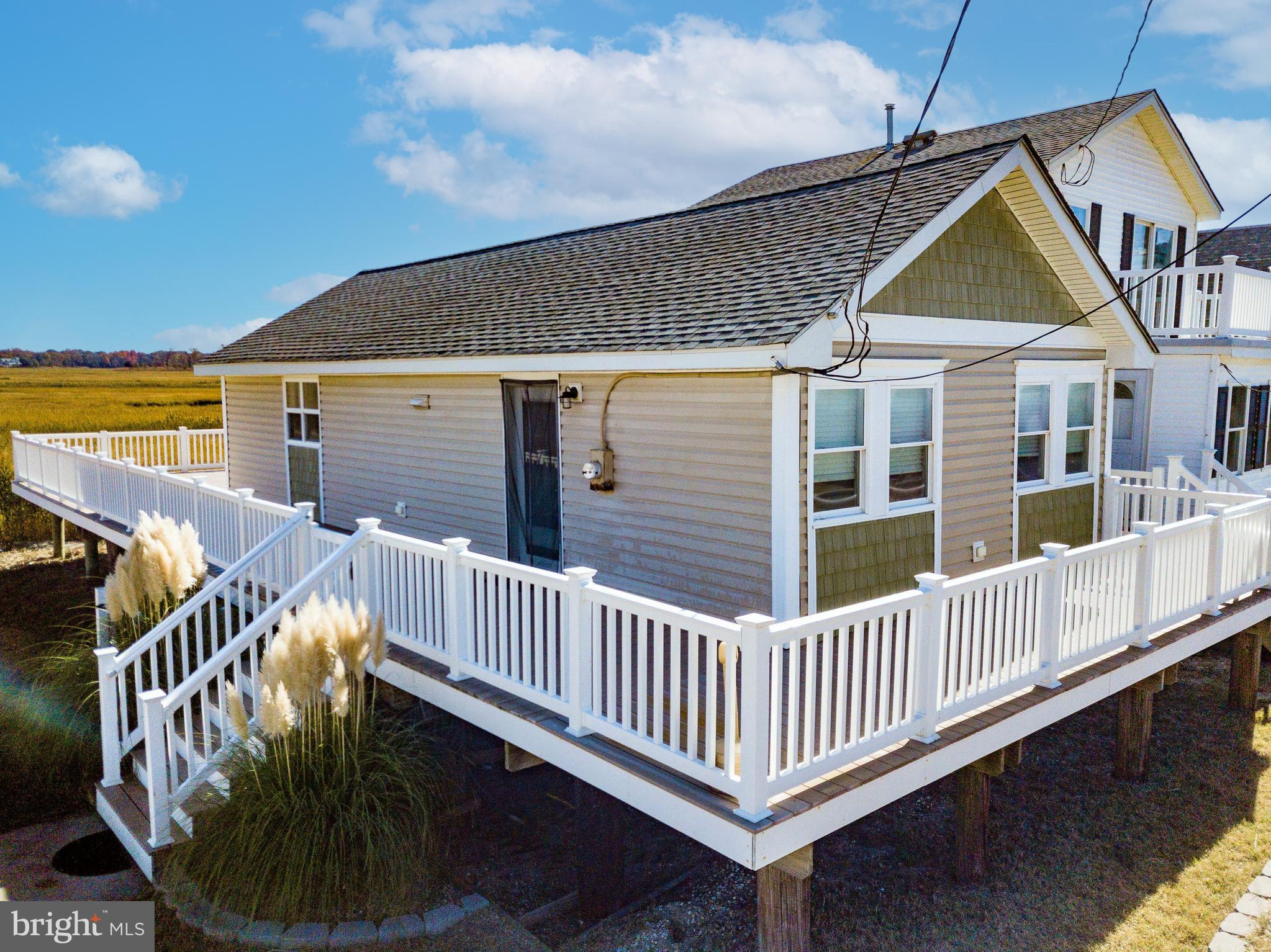 a view of a house with wooden deck stairs and furniture