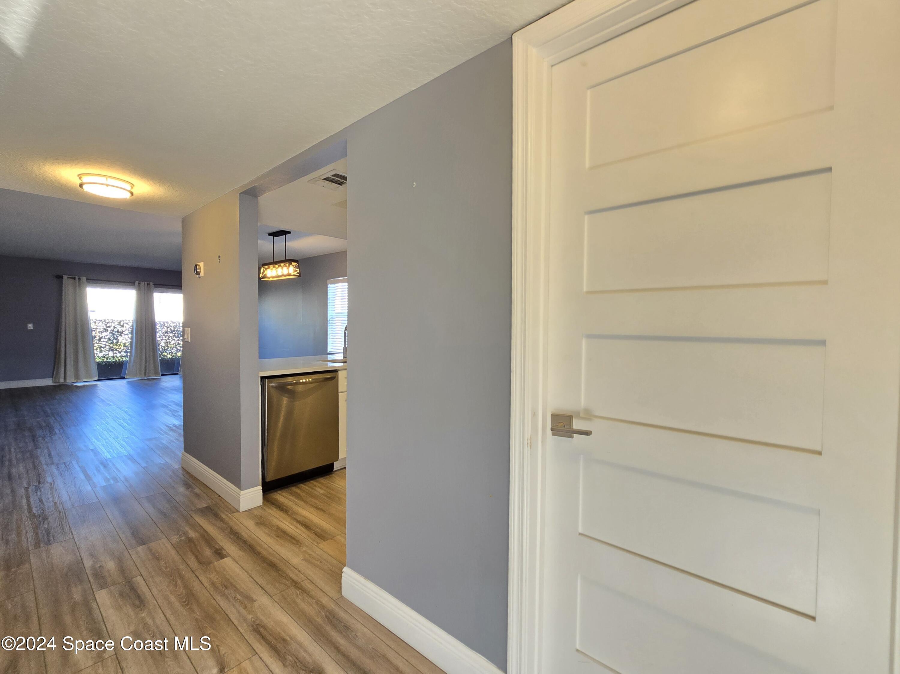 a view of a hallway with wooden floor and a bathroom