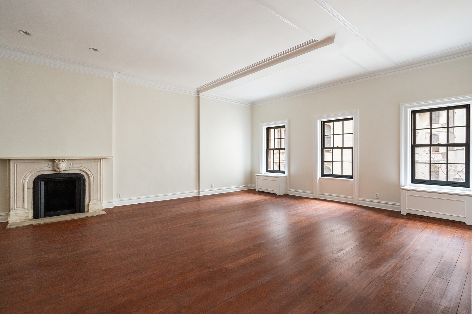 an empty room with windows and fireplace