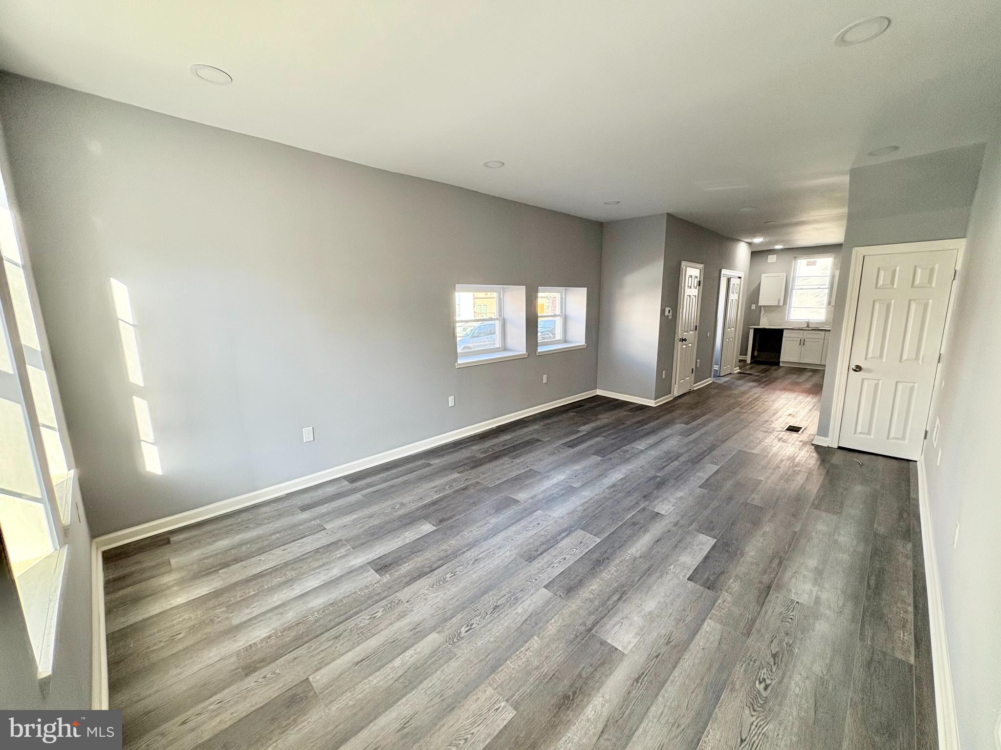 a view of a hallway with wooden floor and windows