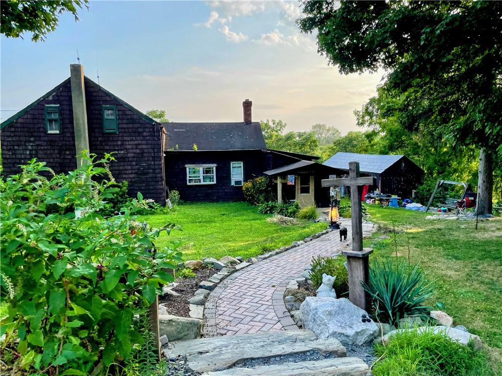 side of home professionally landscaped walk way at dusk featuring a lawn