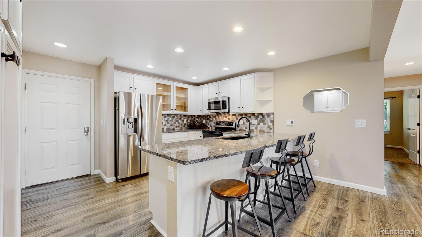 a kitchen with stainless steel appliances granite countertop a refrigerator and a stove top oven