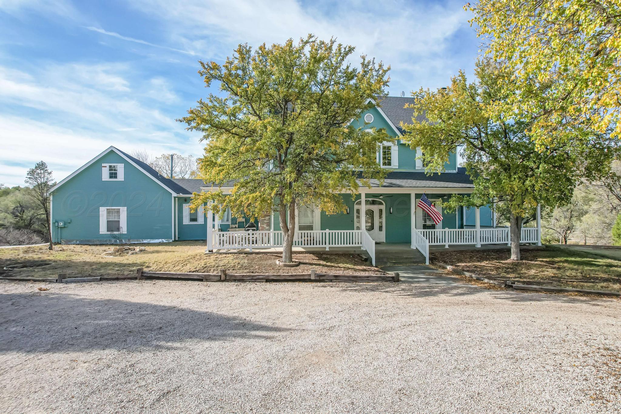 a view of a house with a yard and large tree