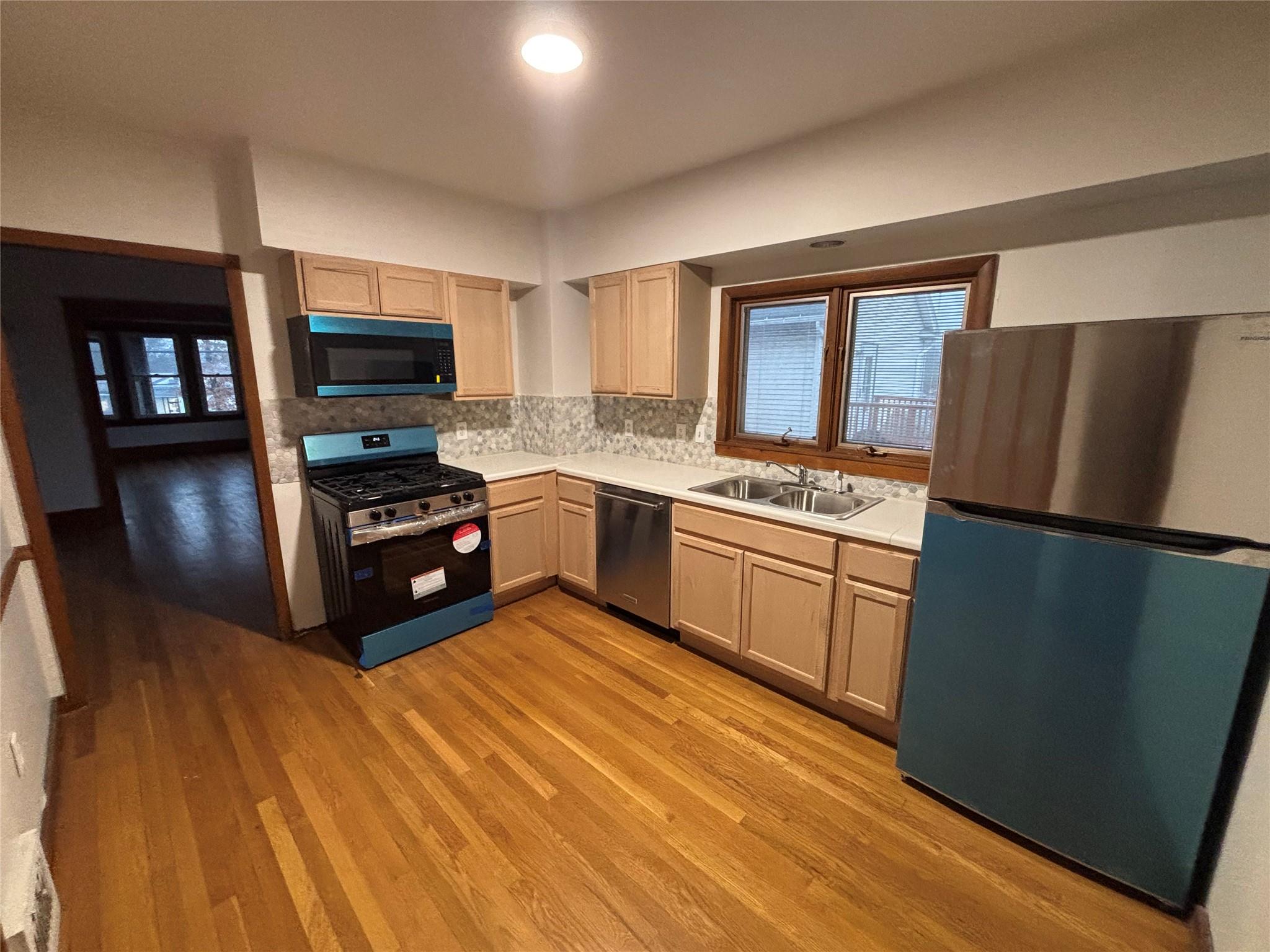 Kitchen featuring light brown cabinetry, sink, stainless steel appliances, and light hardwood / wood-style flooring