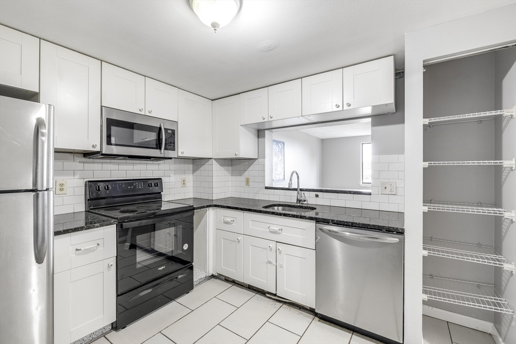 a kitchen with granite countertop white cabinets stainless steel appliances and a sink