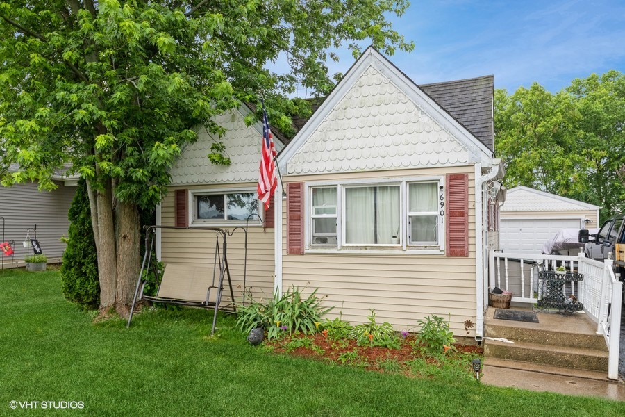 a view of a house with a yard plants and large tree