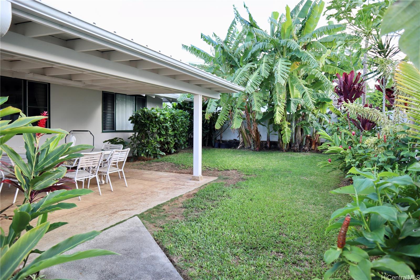 a view of a patio with table and chairs potted plants and floor to ceiling window