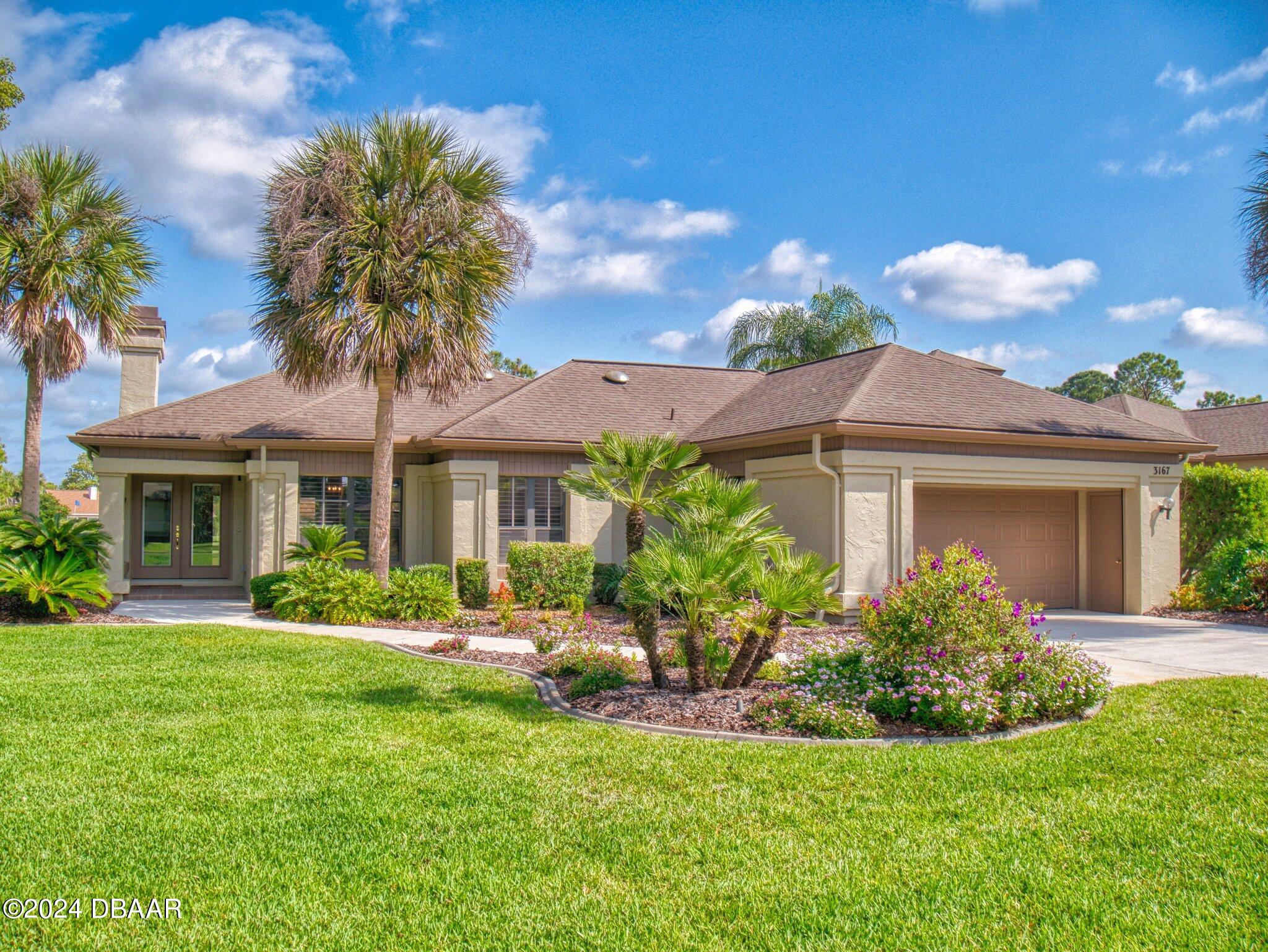 a front view of a house with garden and trees