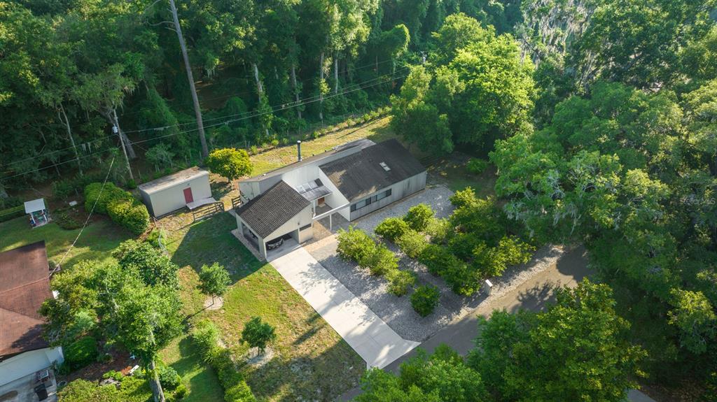 an aerial view of residential house with outdoor space and trees all around