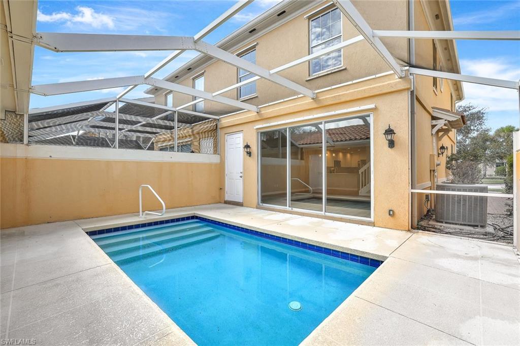 View of pool featuring a patio, central AC, and glass enclosure