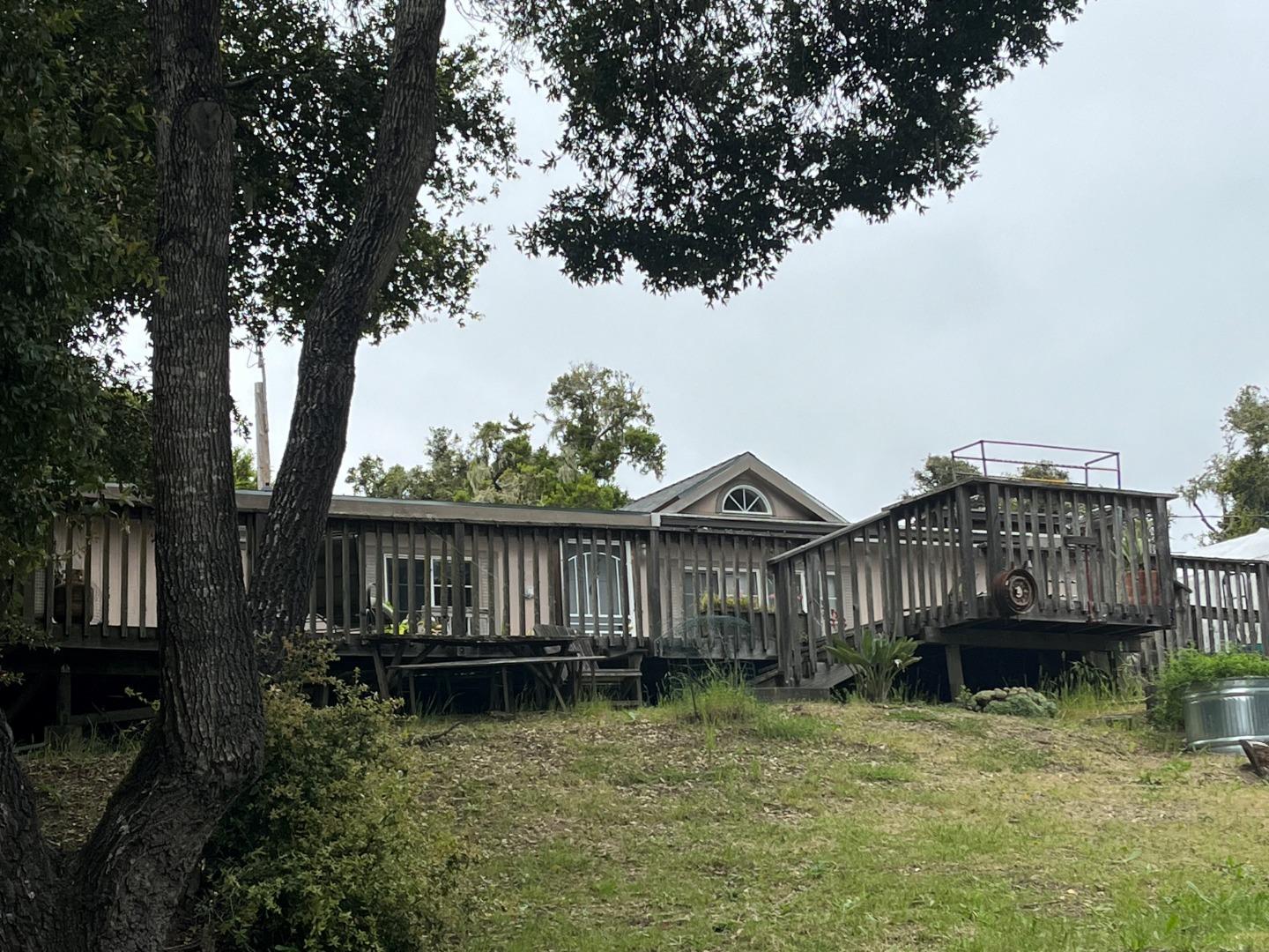 a view of a house with a wooden deck and a forest