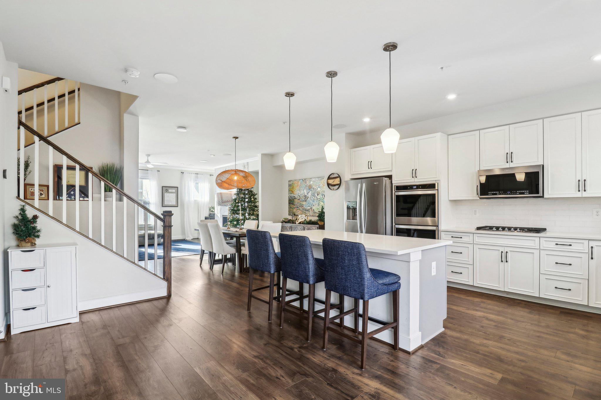 a kitchen with stainless steel appliances kitchen island granite countertop a stove a refrigerator a kitchen island a dining table and chairs with wooden floor