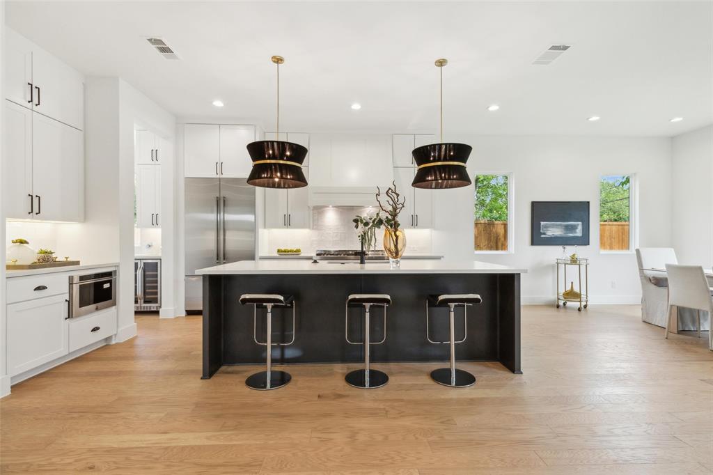 a kitchen with stainless steel appliances a dining table chairs stove and cabinets