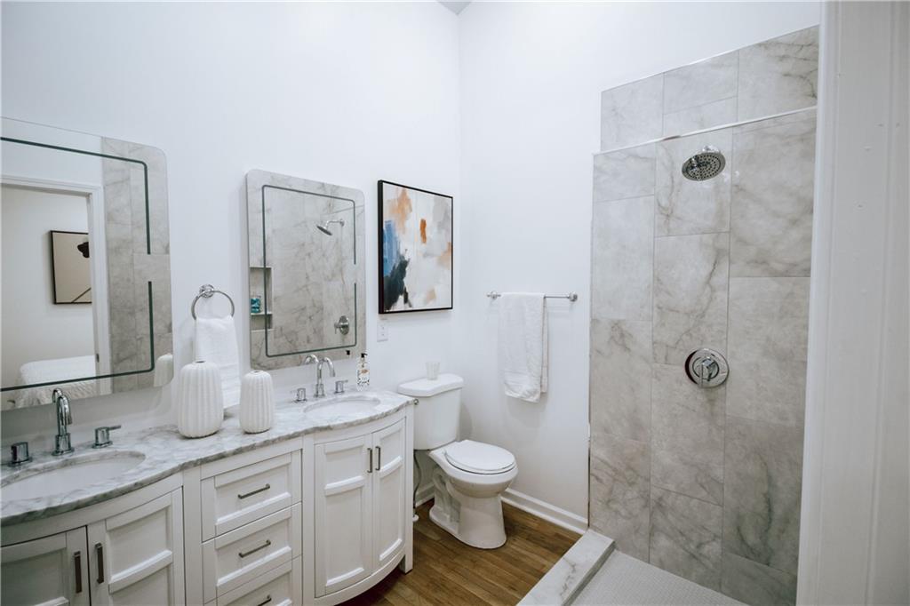 a bathroom with a granite countertop toilet a shower a sink and mirror