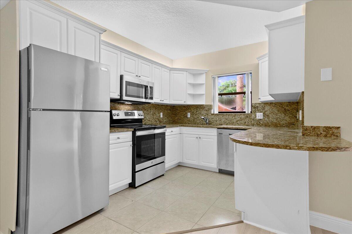 a kitchen with granite countertop white cabinets and white appliances