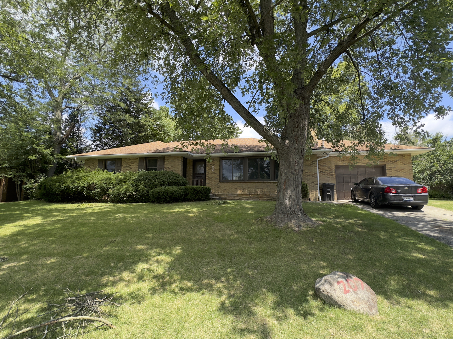 a front view of a house with a garden and trees