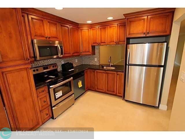 a kitchen with stainless steel appliances granite countertop a refrigerator a stove a sink and dishwasher