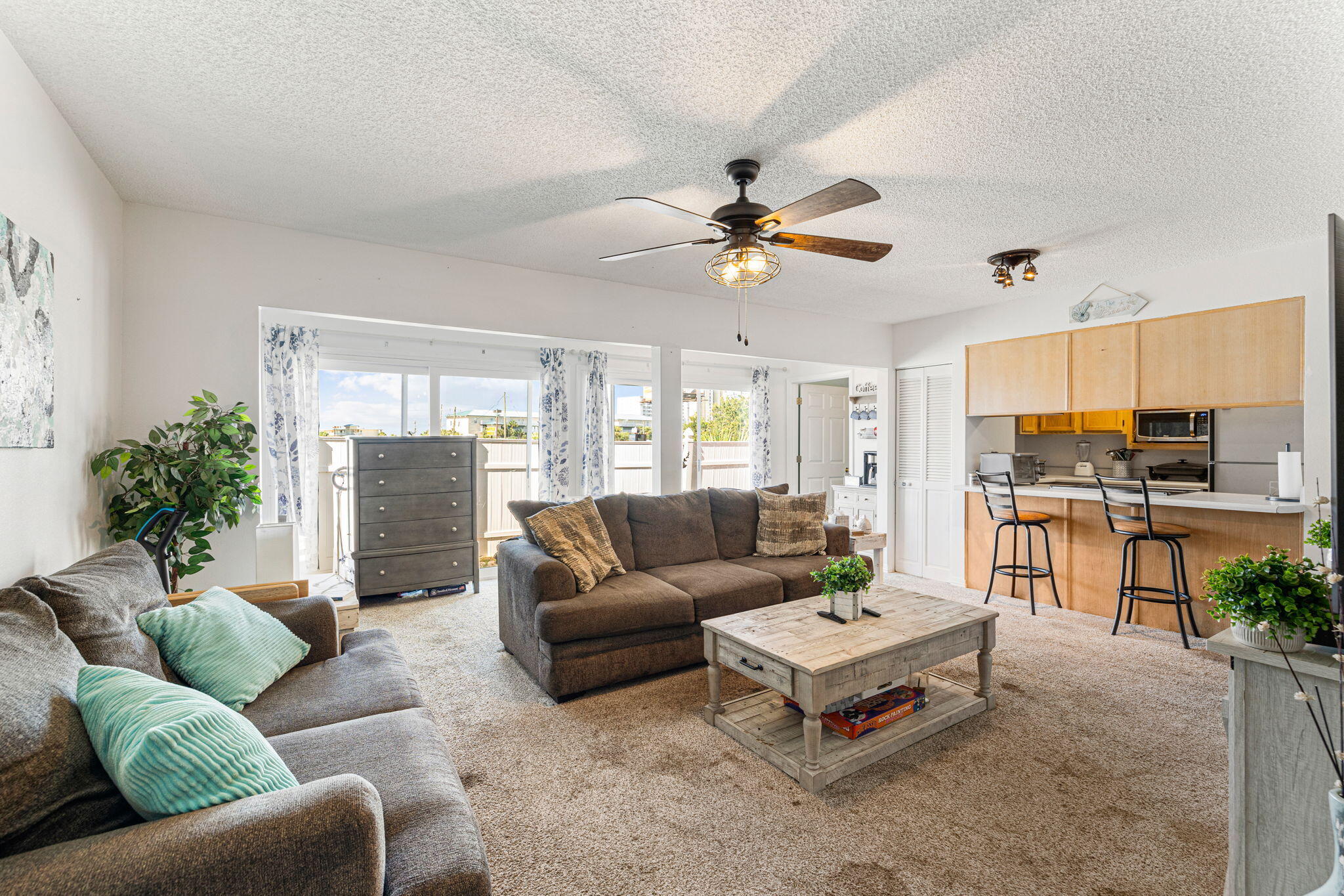 a living room with furniture kitchen view and a large window