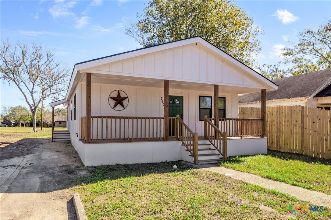 a view of a house with a yard and wooden fence